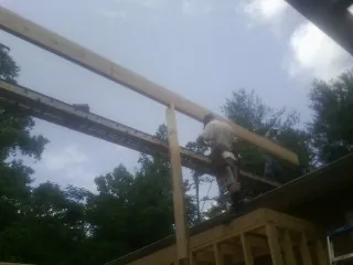 Carpenter setting a ridge beam over a new addition frame — Ice Dam Removal by Roofing Brothers in Navarre