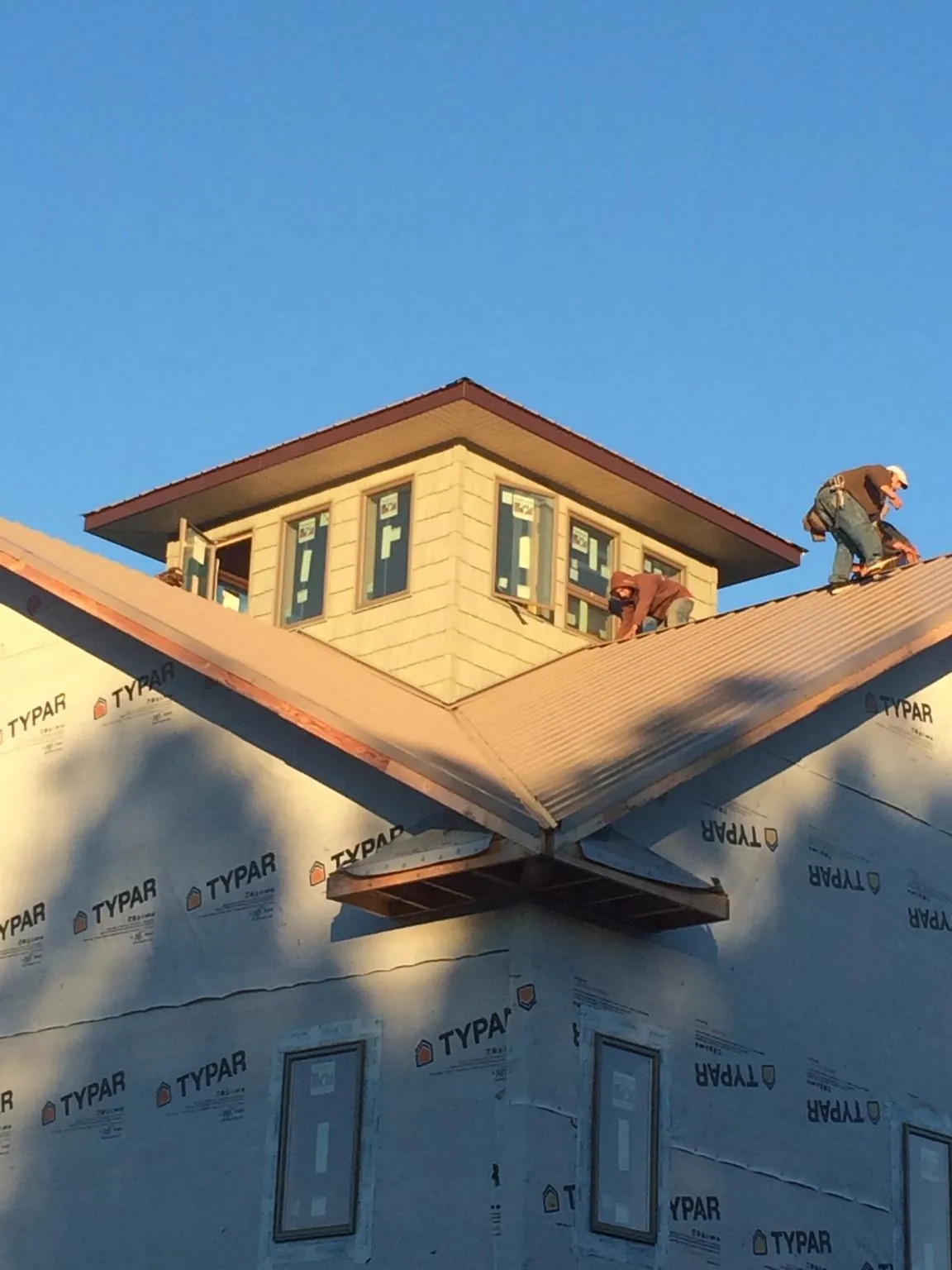 Roofers working around a rooftop cupola on a new metal roof at sunset — Roof Waterproofing in Navarre by Roofing Brothers